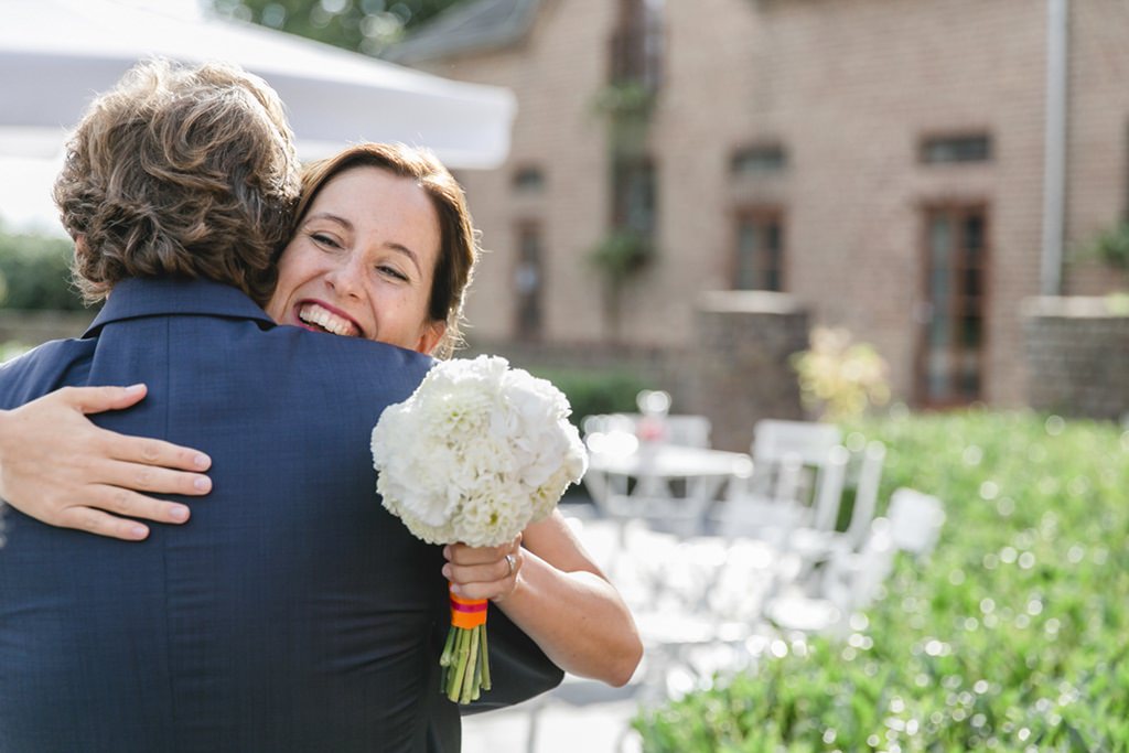 Die glückliche Braut umarmt einen Gast - Photo by Hanna Witte