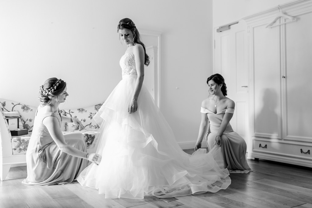 Braut während sie ihr Hochzeitskleid anzieht
