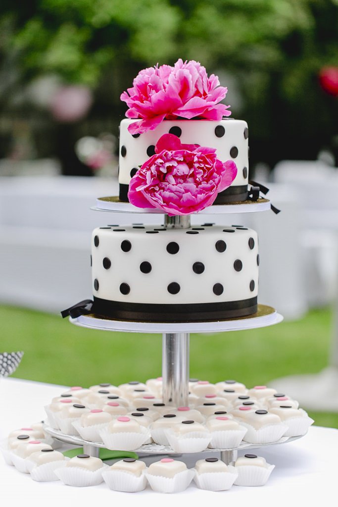 weiße Fondant Hochzeitstorte mit schwarzen Punkten und pinkfarbenen Blumen