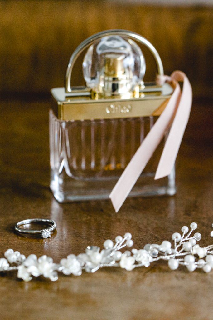 ein Verlobungsring mit Diamant wird vor einem Parfum Flacon fotografiert
