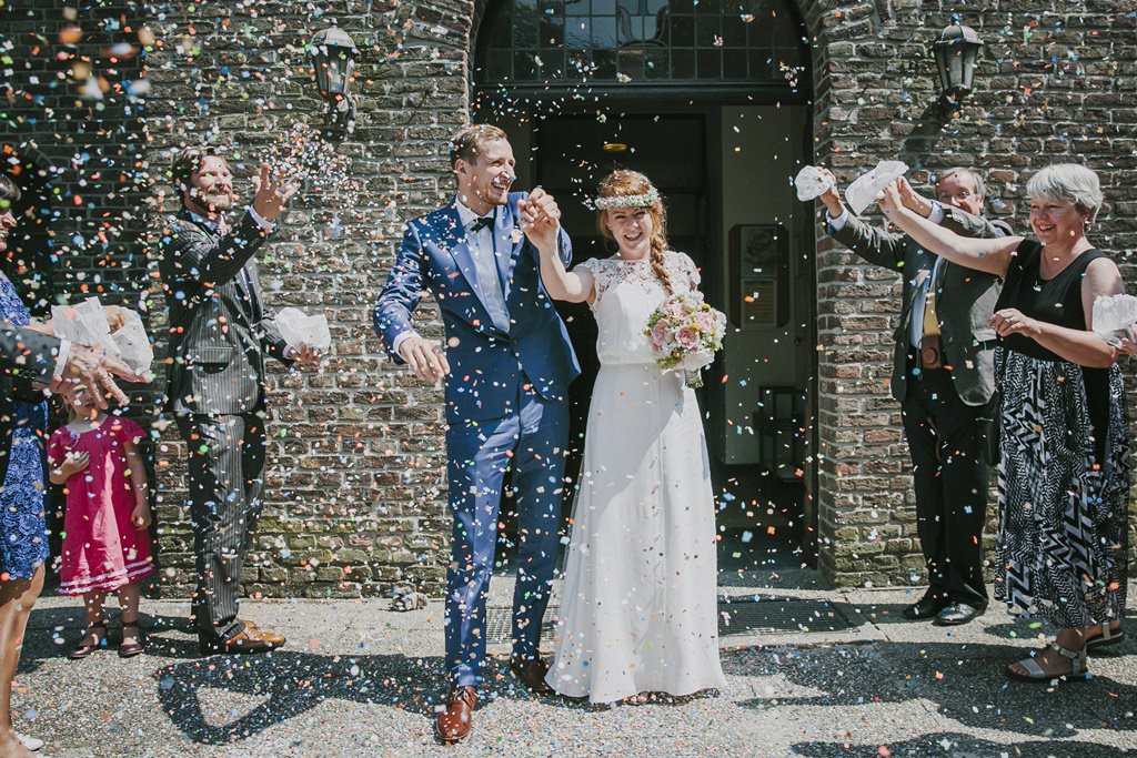 Hochzeitsfoto Idee vom Auszug aus der Kirche: Braut ud Bräutigam werden von den Gästen mit viel Konfetti empfangen