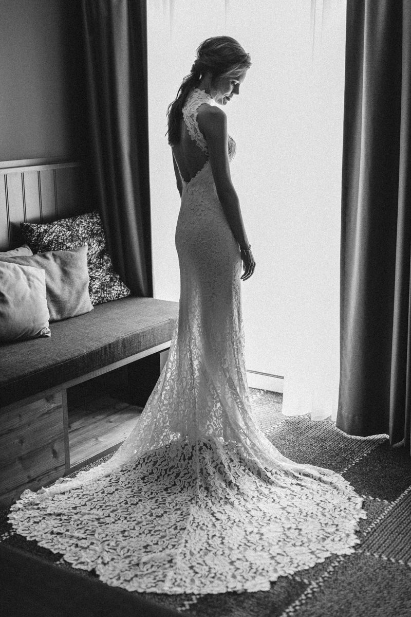 Hochzeitsfoto Idee vom Getting Ready: Schwarz weiß Portrait der Braut vor einem Fenster in ihrem Brautkleid mit Schleppe