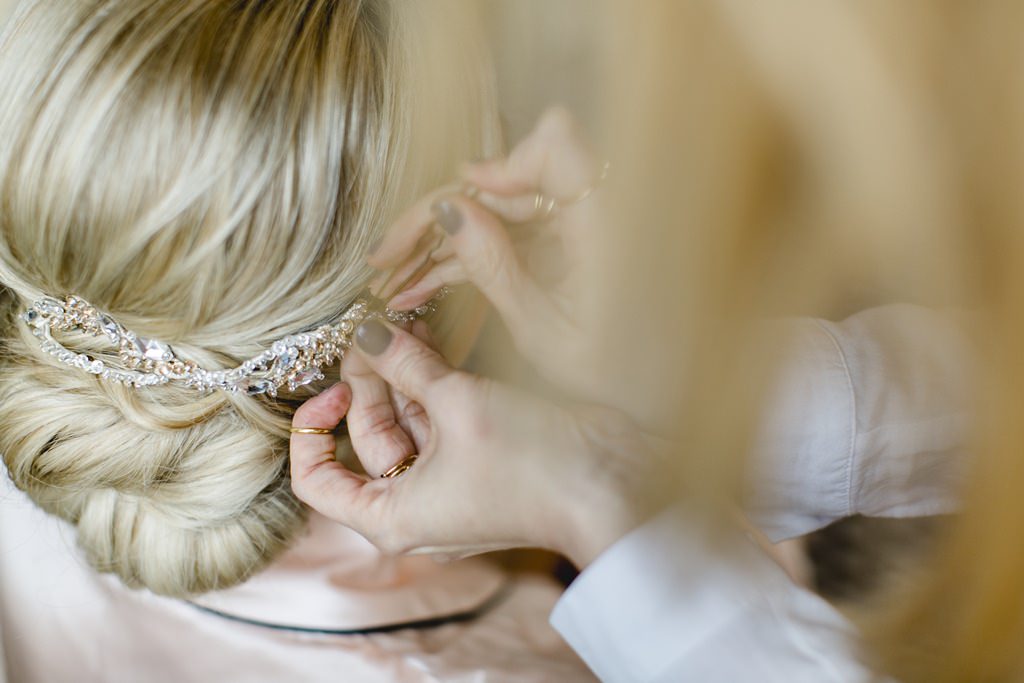 Hochzeitsfoto Idee vom Getting Ready: Der Braut wird der Haarschmuck in die Brautfrisur gesteckt