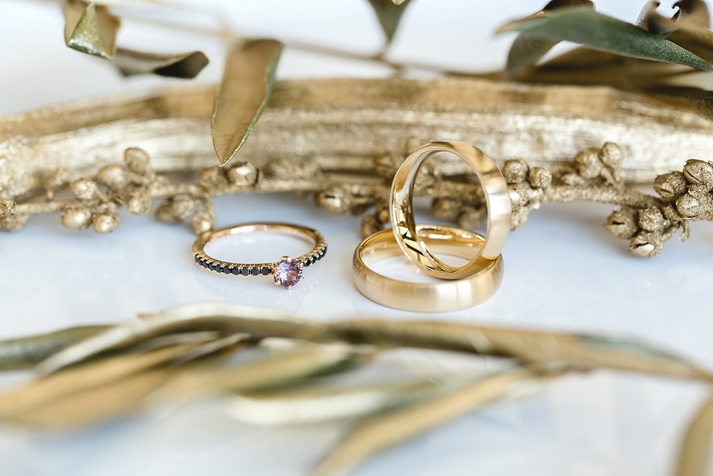 goldener Verlobungsring und goldene Eheringe bei einer eleganten Hochzeitsinspiration