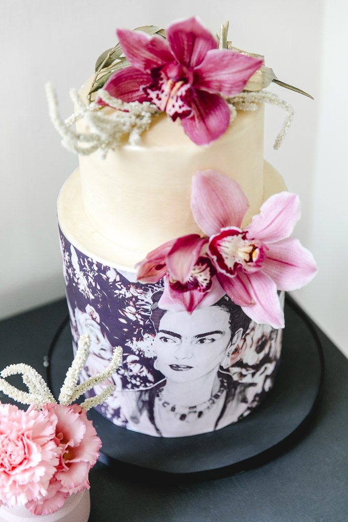 Hochzeitstorte mit Frida Kahlo Motiv und rosa Blütenschmuck
