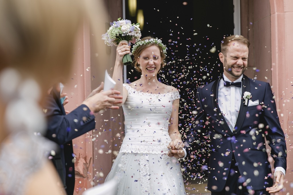 Hochzeitsfoto Idee: Das Brautpaar wird bei Auszug aus der Kirche mit Konfettiregen empfangen
