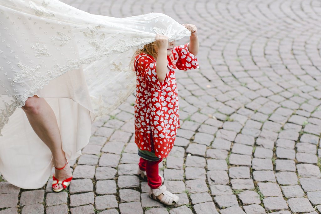 Lustige Hochzeitsfoto Idee: Ein Blumenkind versteckt sich unterm Hochzeitskleid