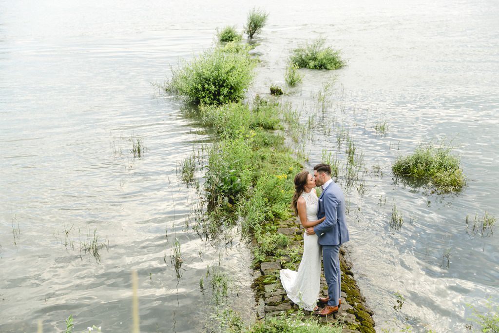 Hochzeitsfotoidee am Wasser: Braut und Bräutigam küssen
