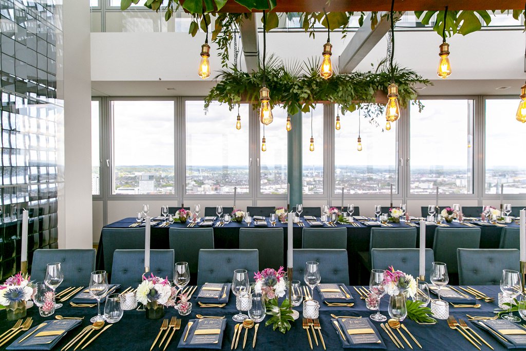 Hochzeitsdeko mit Greenery und Industrial Lights, die über den Tischen hängen | Foto von Hanna Witte Hochzeitsreportagen