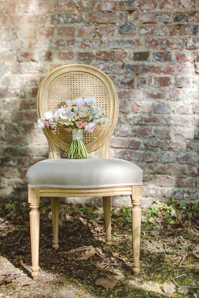 Sommer Brautstrauß mit Rosen, Orchideen und Schleierkraut, der auf einem antiken Stuhl liegt
