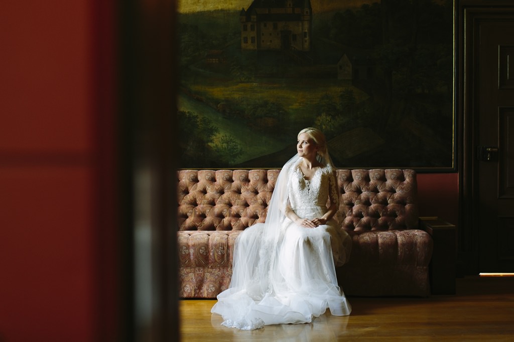 die Braut sitzt vor einem antiken Gemälde von Schloss Körtlinghausen | Foto von Hanna Witte