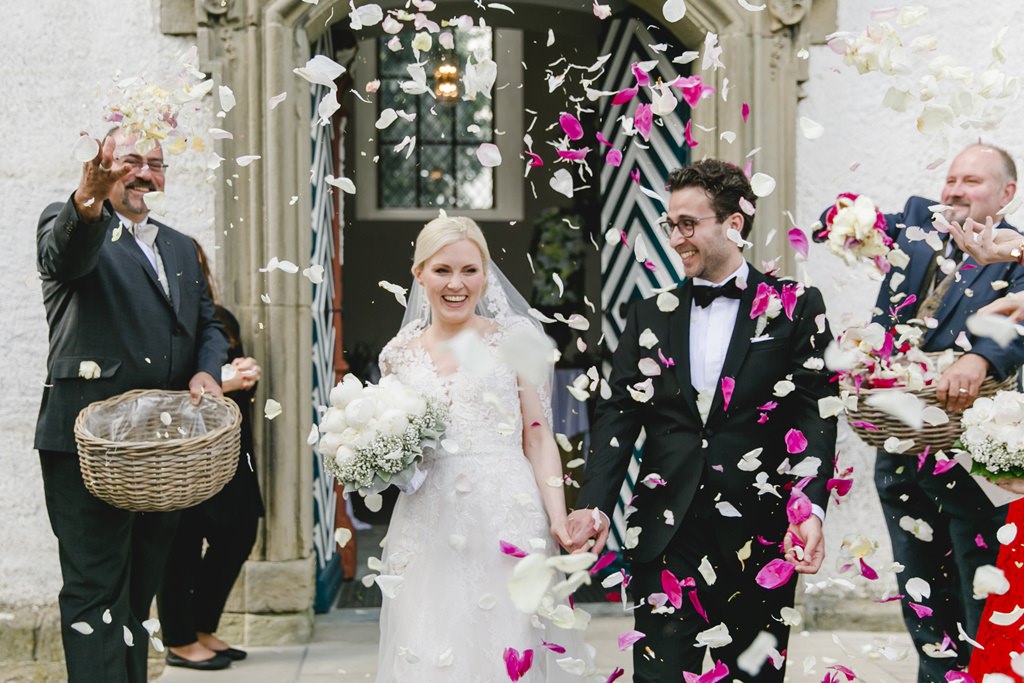 Hochzeitsfoto von Braut und Bräutigam im Streublüten-Meer beim Auszug aus der Kirche | Foto von Hanna Witte