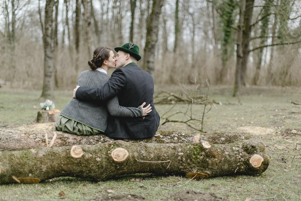 ein Brautpaar in Tracht küsst sich auf einem Baumstamm | Foto: Hanna Witte