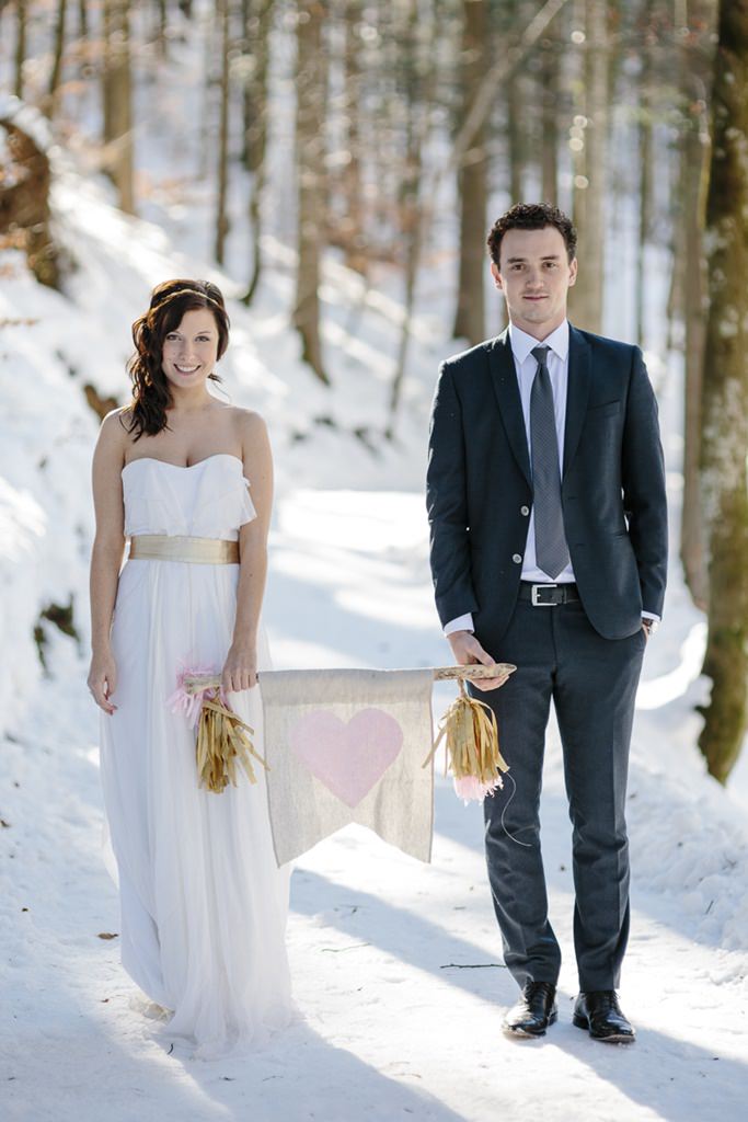Braut und Bräutigam stehen für ein Paarfoto mit einem Herzwimpel im Schnee | Foto: Hanna Witte