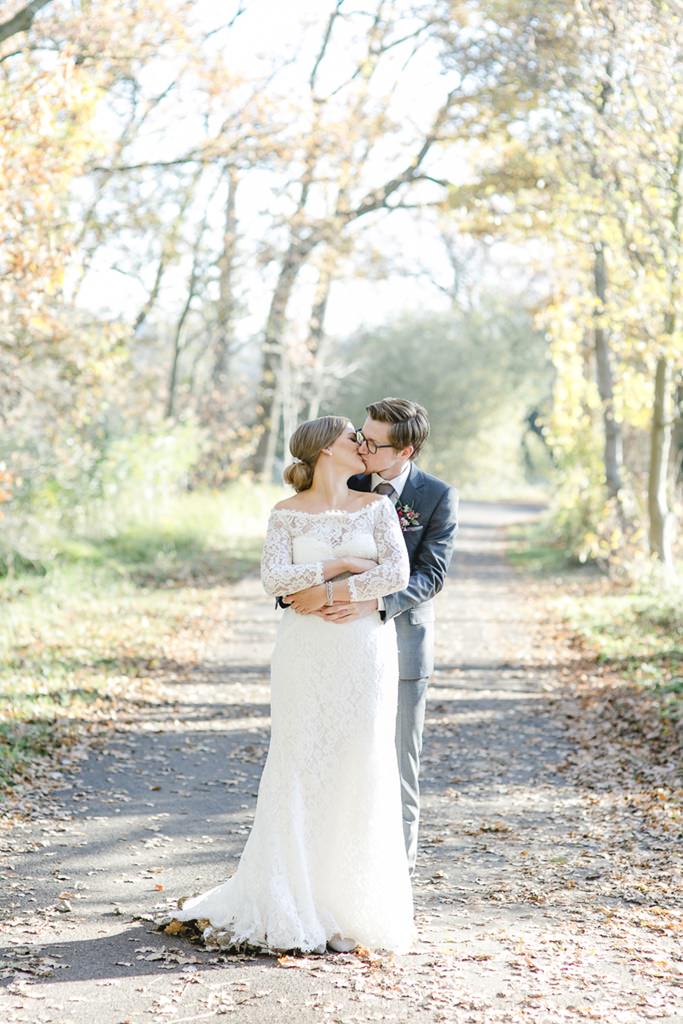 Braut und Bräutigam küssen sich auf einem Weg voller Laub | Foto: Hanna Witte