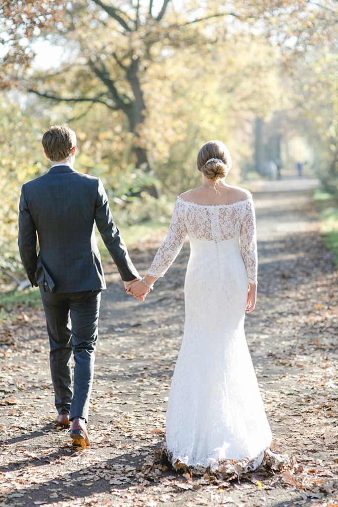 Braut und Bräutigam laufen Hand in Hand durch einen Wald voller Laub | Foto: Hanna Witte