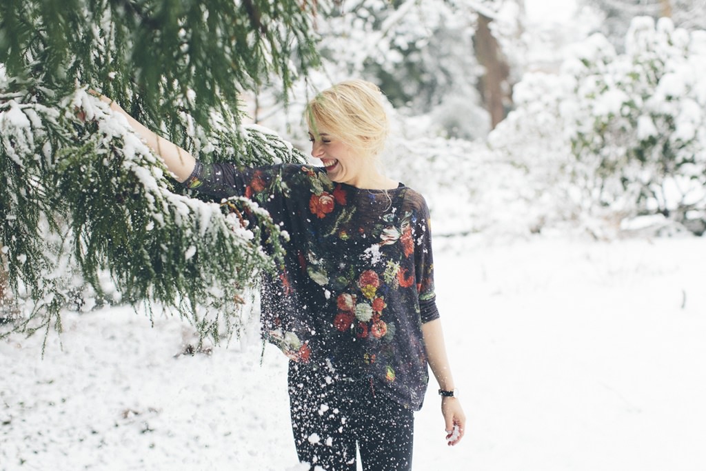 eine Frau rüttelt an einer Tanne voller Schnee | Foto: Hanna Witte