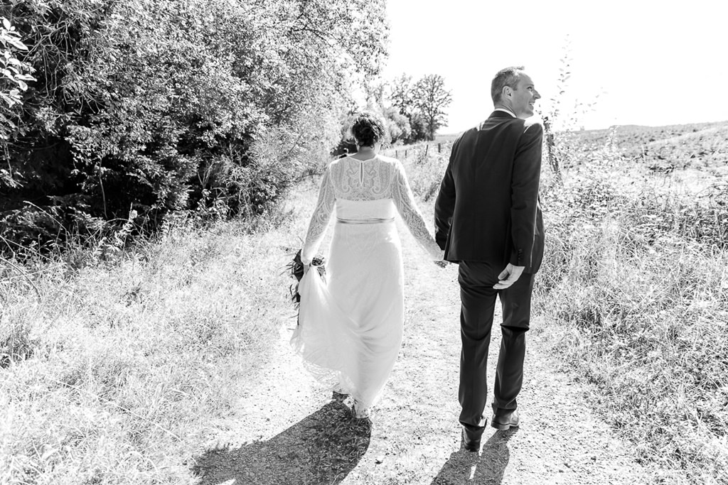 bei einer Hochzeit im Sauerland laufen Braut und Bräutigam über einen Feldweg | Foto von Hochzeitsfotografin Hanna Witte