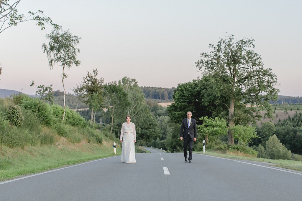 Paarfotoidee draußen: Braut und Bräutigam stehen auf einer verlassenen Straße im Sauerland | Foto von Hochzeitsfotografin Hanna Witte