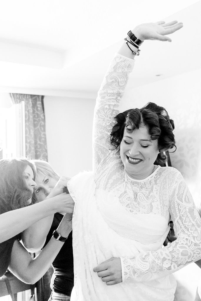 Freundinnen helfen der Braut beim Anziehen ihres Brautkleides | Foto von Hochzeitsfotografin Hanna Witte