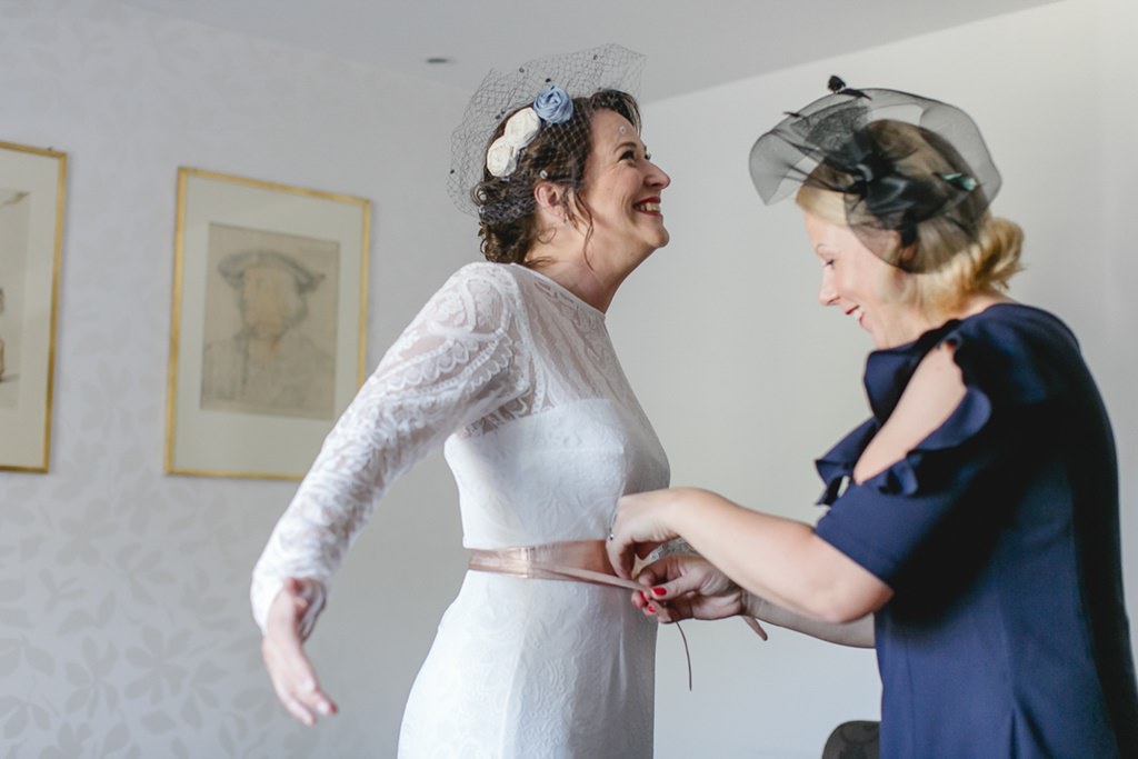 eine Freundin hilft der Braut beim Getting Ready das Brautkleid zu richten | Foto von Hochzeitsfotografin Hanna Witte