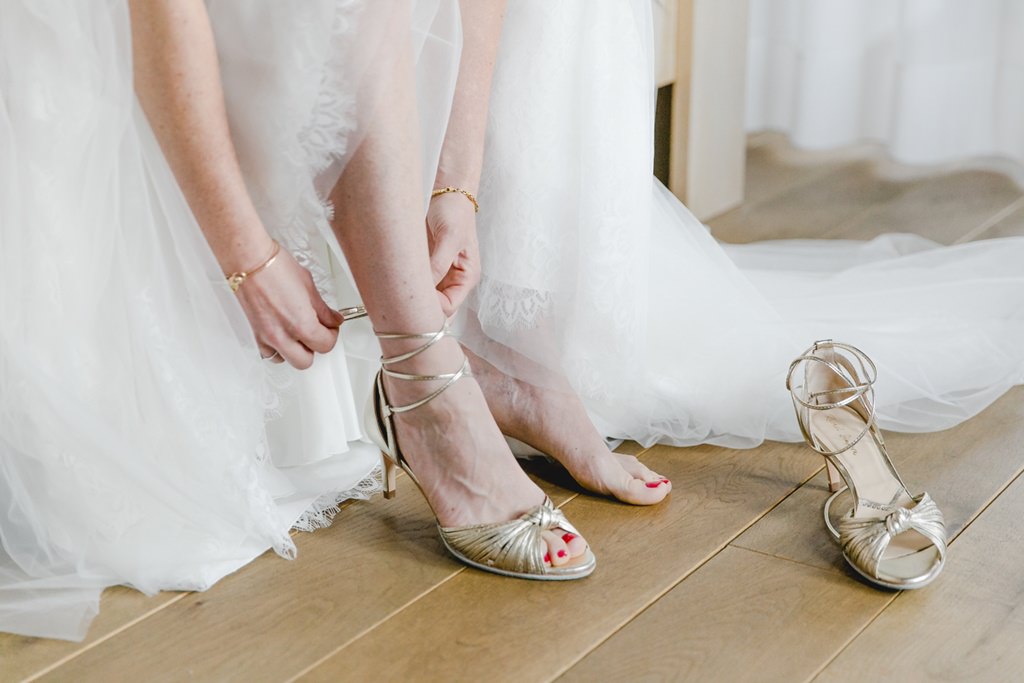 die Braut zieht sich beim Getting Ready ihre goldenen Brautschuhe an | Foto: Hanna Witte