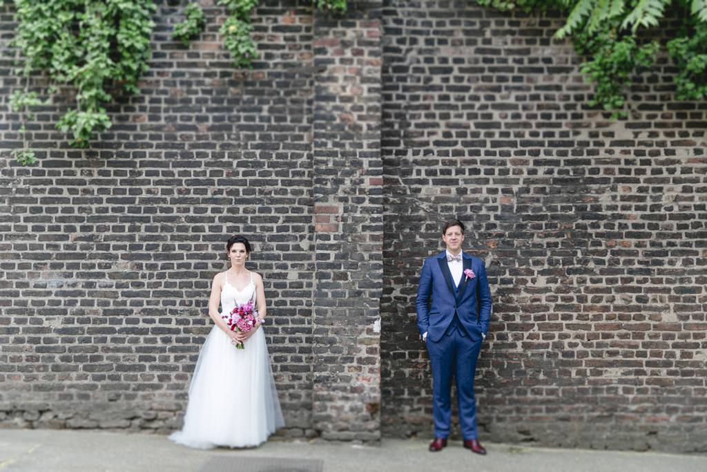cooles Paarfoto von Braut und Bräutigam vor einer Backsteinmauer | Foto: Hanna Witte