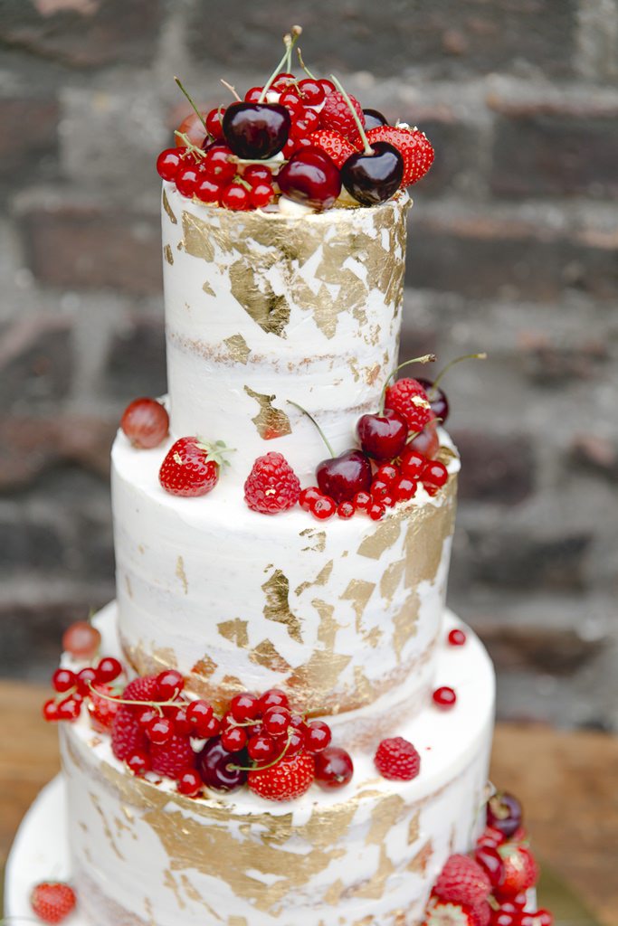 Weiße Hochzeitstorte mit Blattgold und roten Beeren | Foto: Hanna Witte
