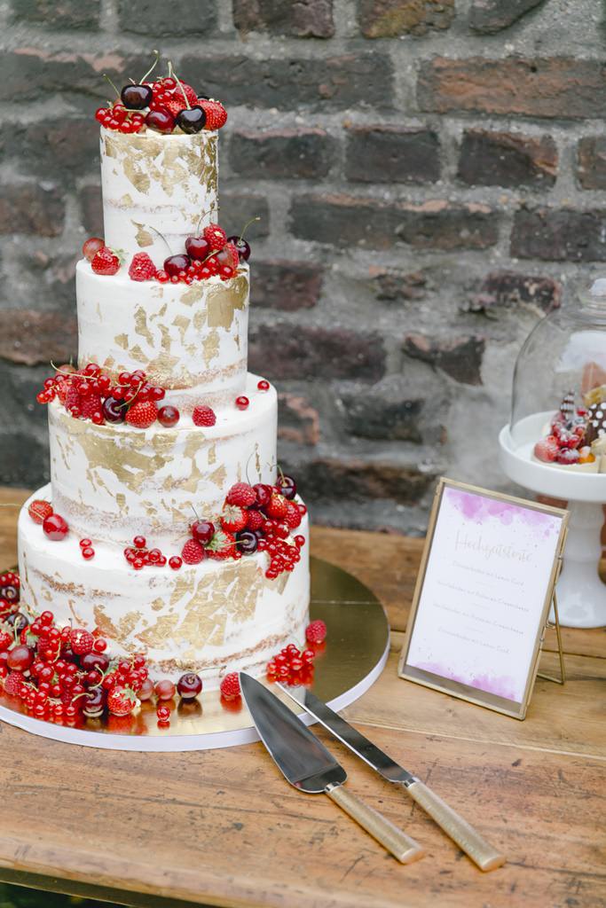 Hochzeitstorte in Weiß und Gold mit roten Früchten | Foto: Hanna Witte