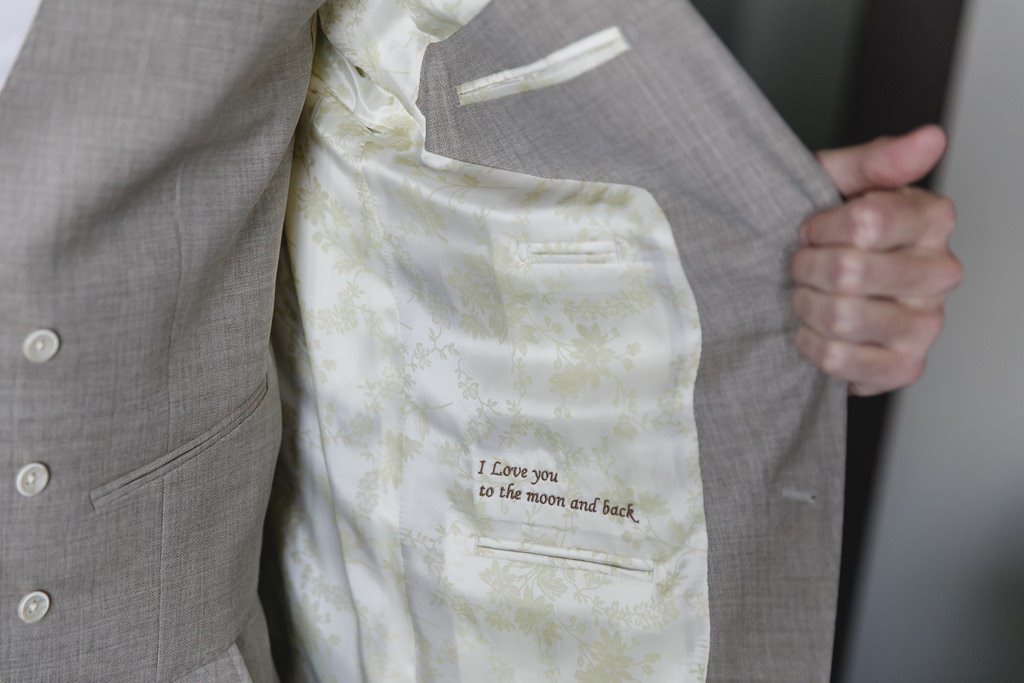der Bräutigam zeigt einen handgestickten Spruch in seinem Maßanzug | Foto: Hanna Witte