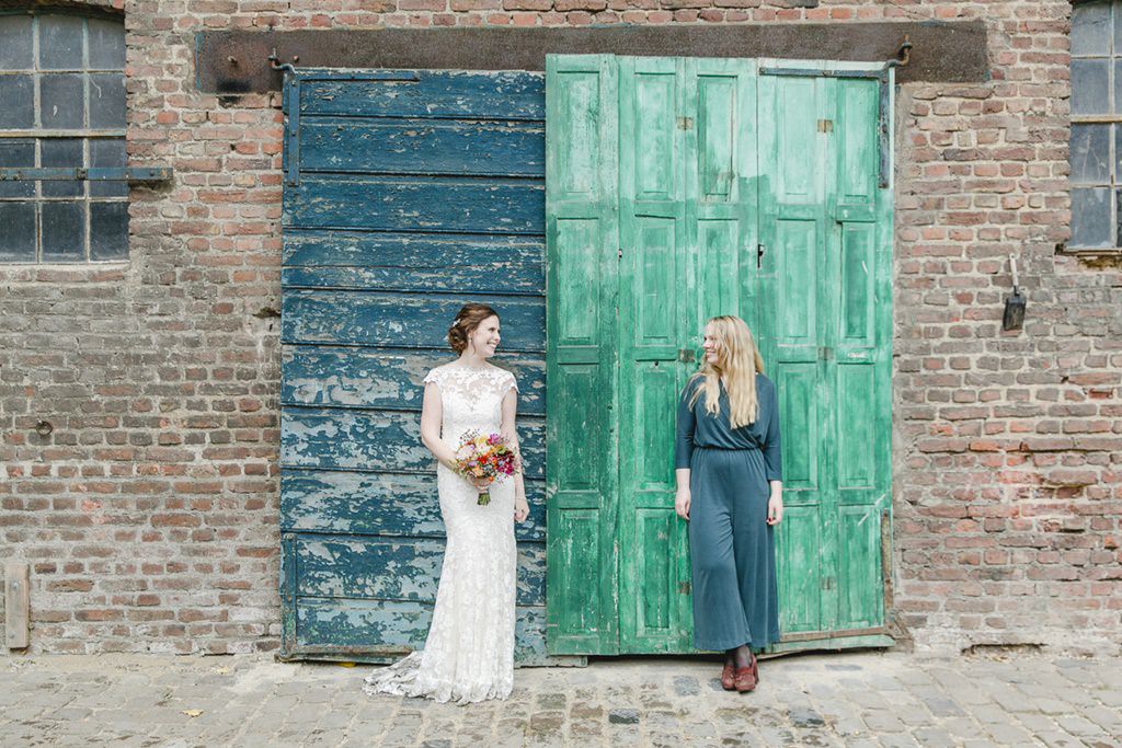 die Braut steht mit ihrer Trauzeugin vor einer alten grünen Holztür | Foto: Hanna Witte