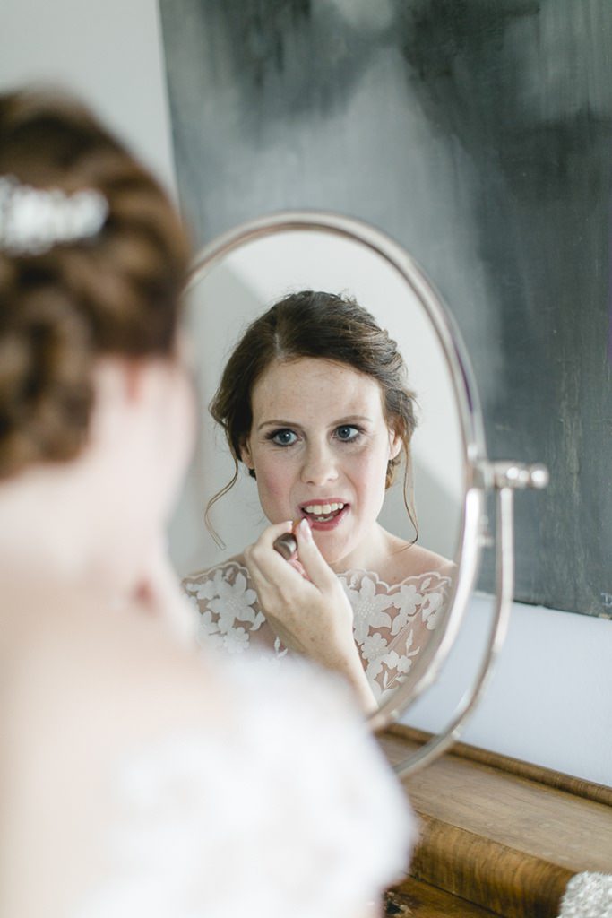 Die Braut trägt beim Getting Ready für die Hochzeit Lippenstift auf | Foto: Hanna Witte