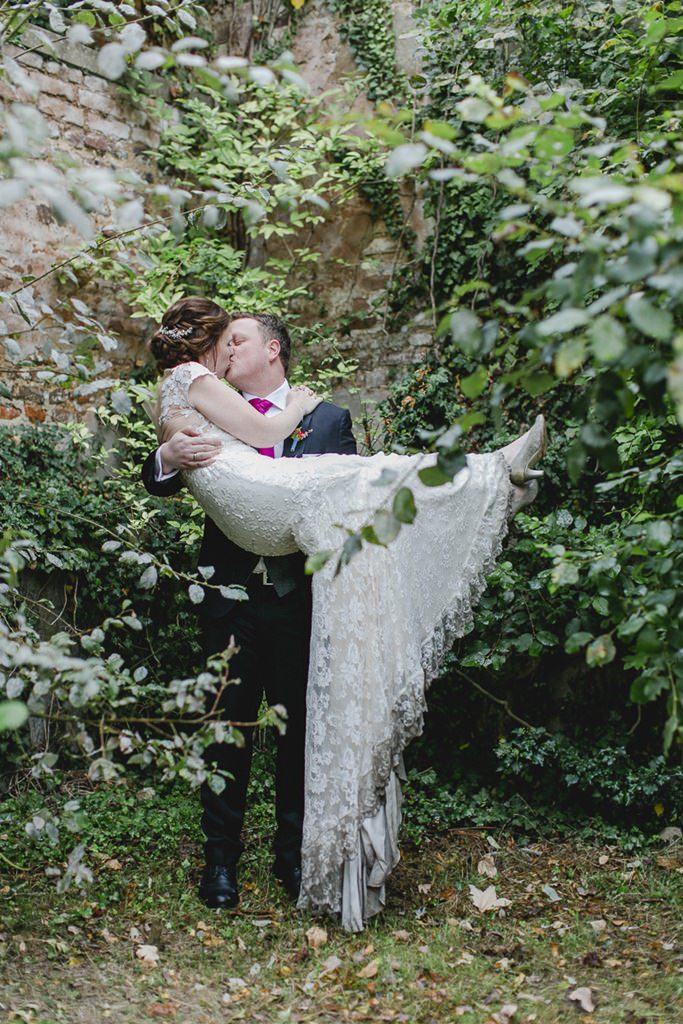 der Bräutigam trägt die Braut in seinen Armen, während sich die beiden küssen | Foto: Hanna Witte