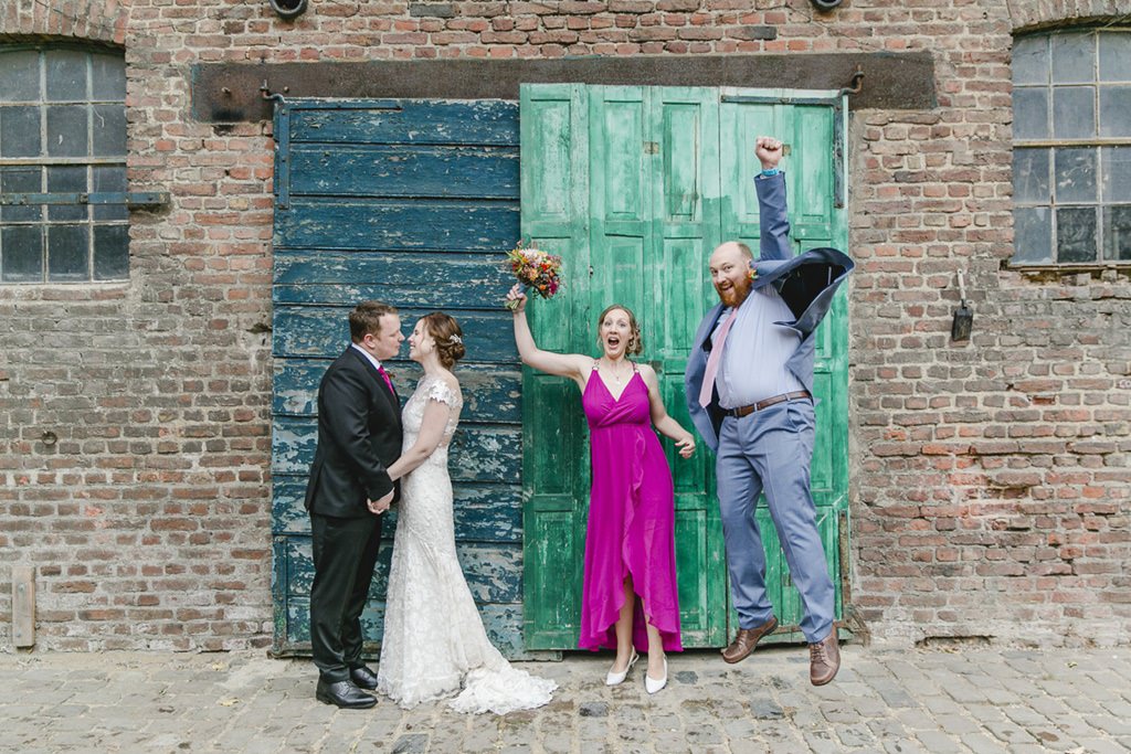 Hochzeitsgruppenfotoidee: Das Brautpaar küsst sich, während 2 Freunde in die Luft springen | Foto: Hanna Witte