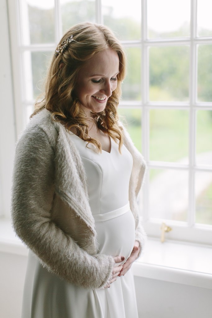 Brautfoto mit Babybauch: Die schwangere Braut streichelt glücklich ihren Bauch | Foto: Hanna Witte