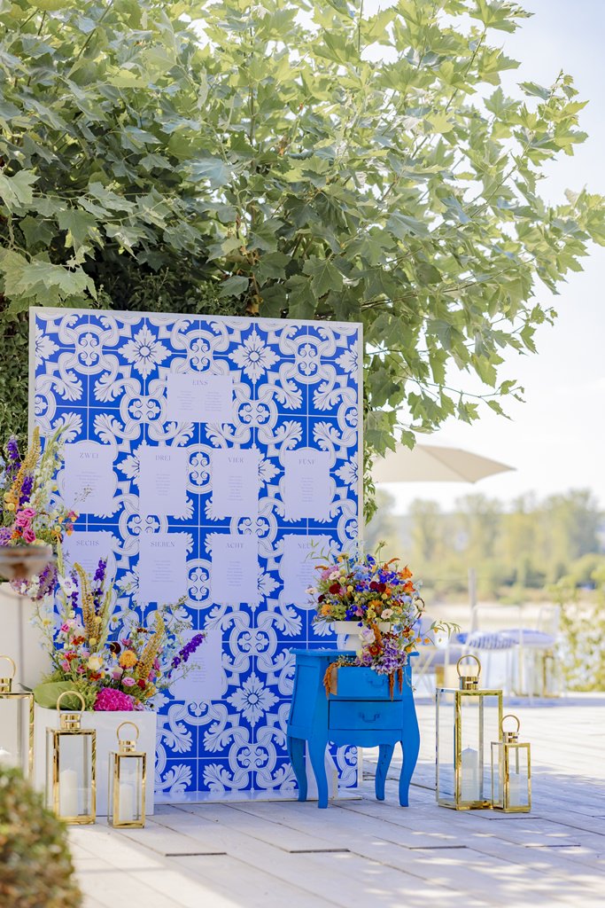 Hochzeits-Sitzplan in blau und weiß, mit bunter Blumendeko und Laternen | Foto: Hanna Witte