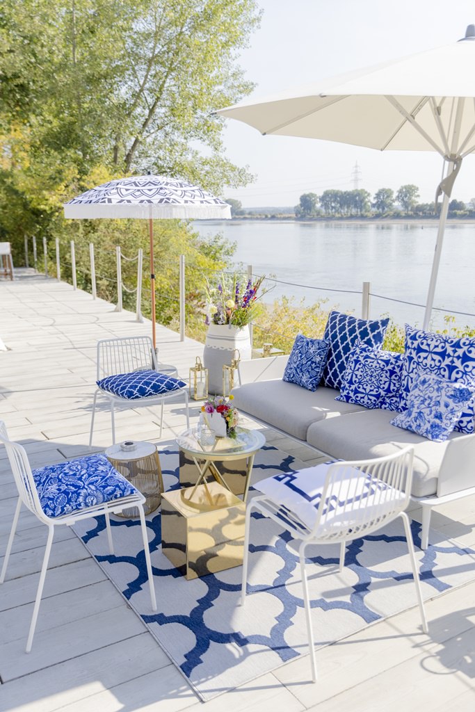 modern gestaltete Sitzecke mit blau-weiß gemusterten Kissen und goldenen Tischen | Foto: Hanna Witte