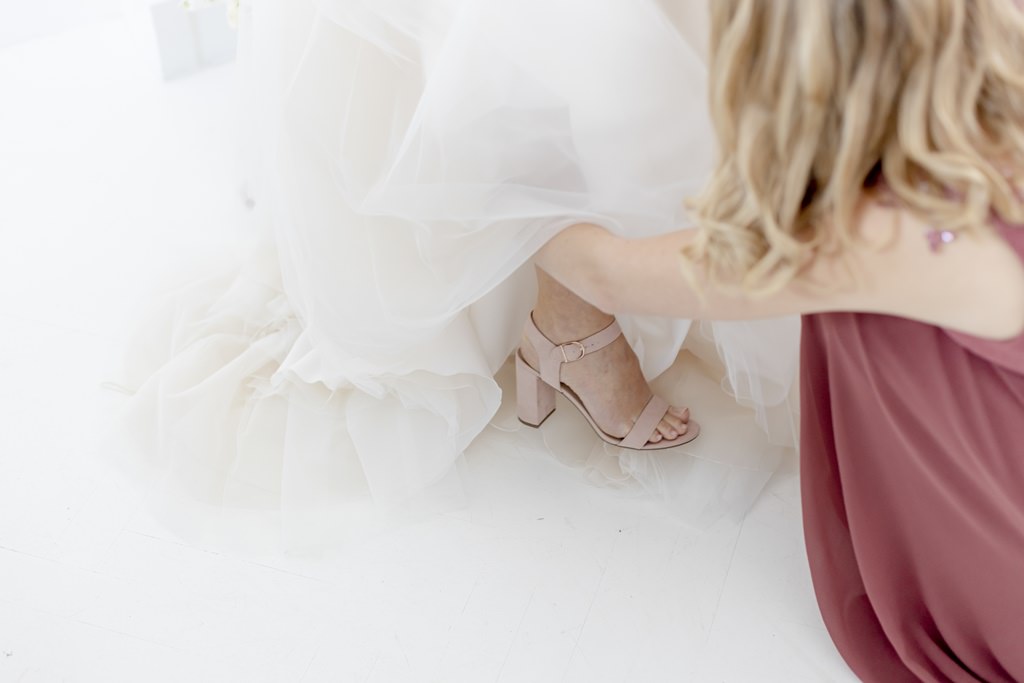 die Brautjungfer hilft der Braut beim Anziehen der Brautschuhe | Foto: Hanna Witte