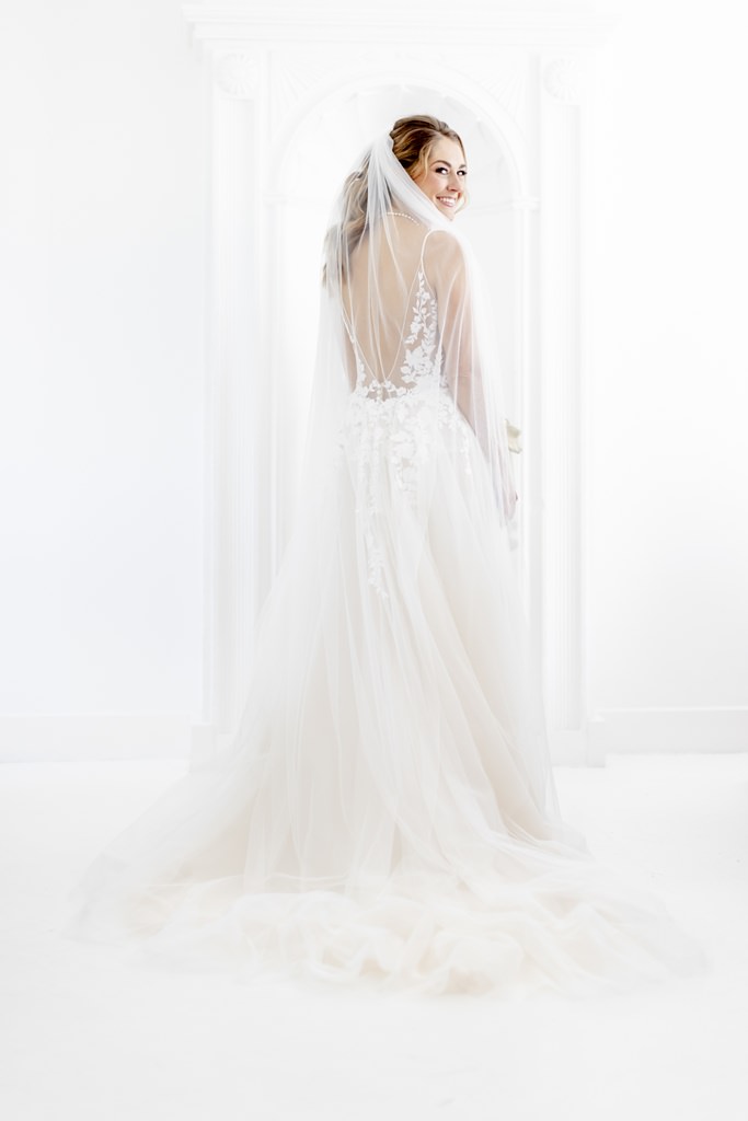 die Braut in ihrem rückenfreien Brautkleid mit Schleppe, Spitze und Schleier | Foto: Hanna Witte