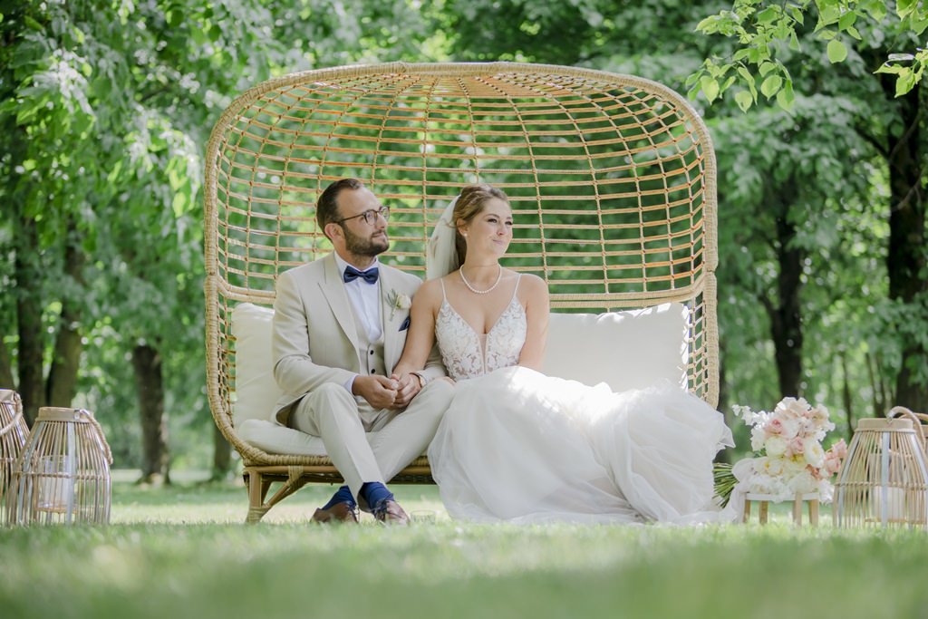das Brautpaar sitzt auf einer modernen Rattan Traubank | Foto: Hanna Witte