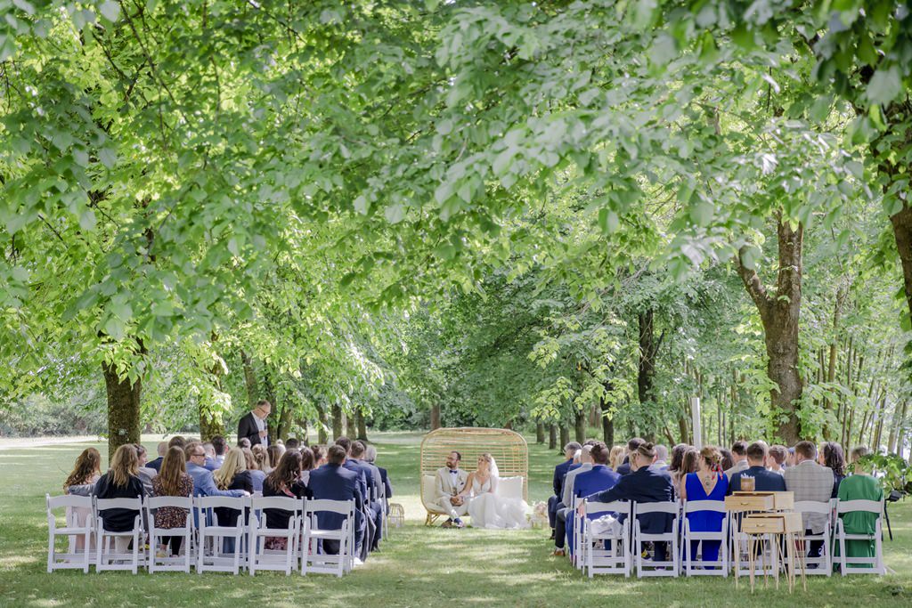 Brautpaar und Gäste während der Freien Trauung unter grünen Bäumen | Foto: Hanna Witte