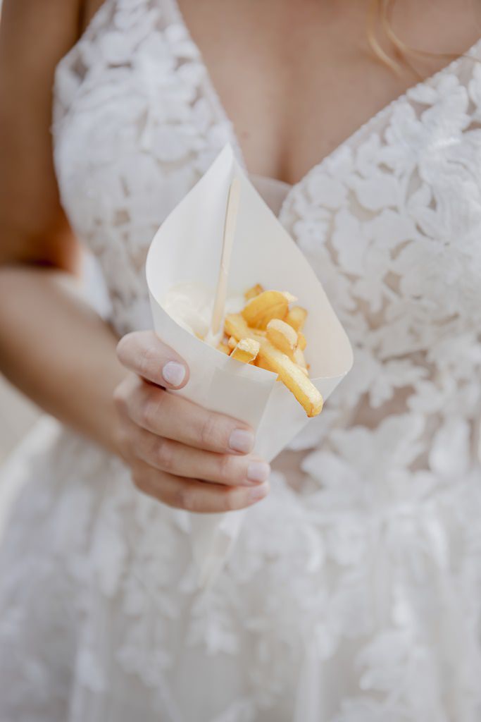 die Braut isst beim Sektempfang Pommes aus der Papiertüte | Foto: Hanna Witte