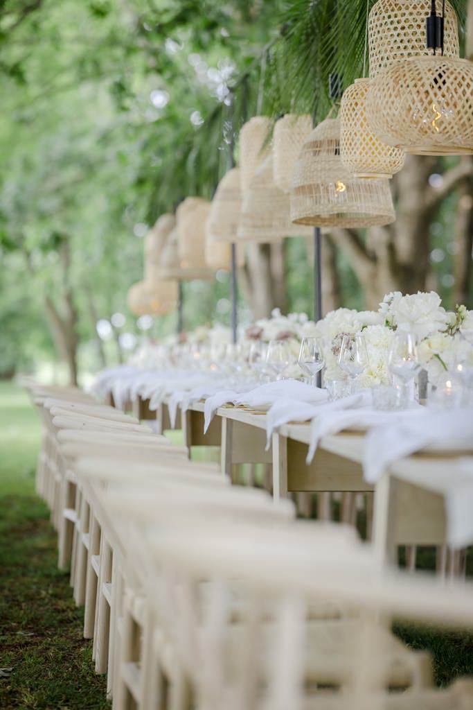 die lange Hochzeitstafel mit heller Deko, Holzstühlen und Rattan Lampenschirmen | Foto: Hanna Witte