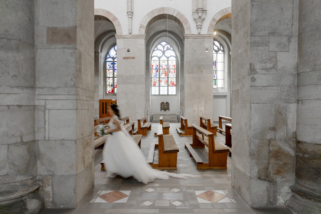 eine Braut läuft mit ihrem Brautstrauß in der Hand durch eine Kirche | Foto: Hanna Witte