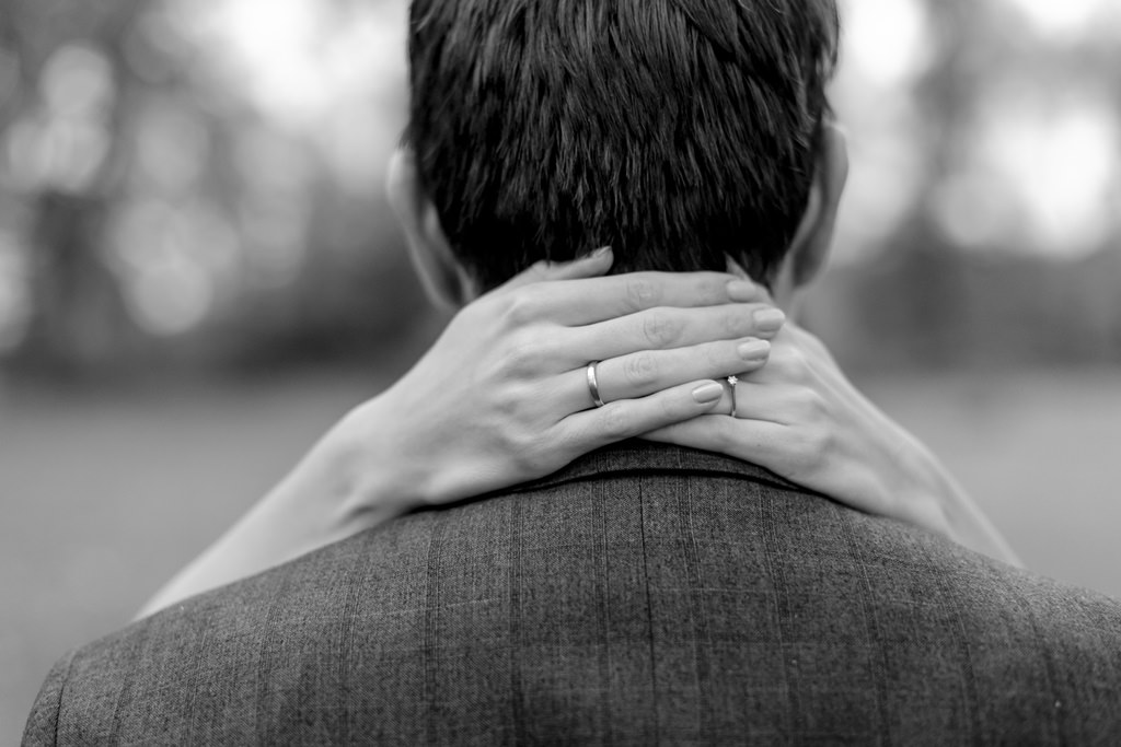 Rückenansicht des Bräutigams, dessen Nacken von den Händen der Braut umfasst wird | Foto: Hanna Witte