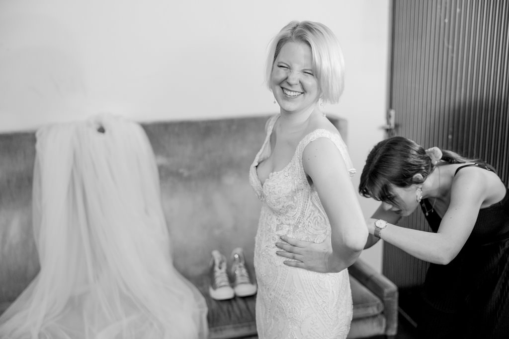 die Trauzeugin schließt das Hochzeitskleid der Braut | Foto: Hanna Witte