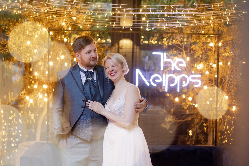 das Brautpaar steht vor einem romantischen Wedding Backdrop aus Lichterketten | Foto: Hanna Witte