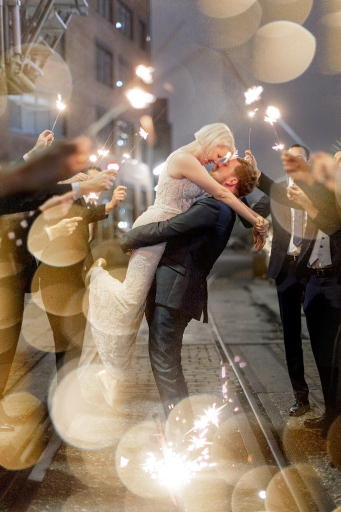 das Brautpaar posiert zwischen Hochzeitsgästen mit Wunderkerzen | Foto: Hanna Witte