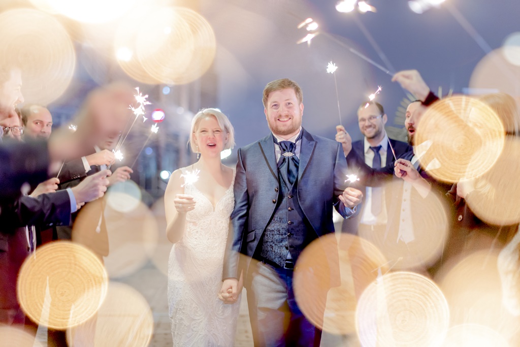ein Brautpaar läuft mit Wunderkerzen in den Händen durch ein Spalier der Hochzeitsgäste, die ebenfalls Wunderkerzen hochhalten | Foto: Hanna Witte