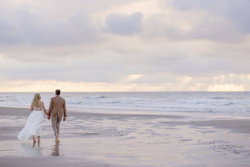 das Brautpaar läuft Hand in Hand am Meer entlang | Foto: Hanna Witte